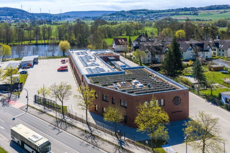 Luftaufnahme der Feuerwache Bad Pyrmont mit Solar-Carports, Photovoltaikanlage auf dem Dach und angrenzendem Parkplatz